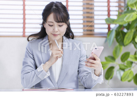 スマホを見ながらスケジュールを確認する若いビジネスウーマン 63227893