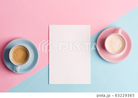 Creative pastel blue pink background with two ceramic cups of freshly brewed coffee drink and paper sheet. 63229365
