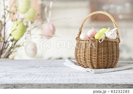 Wicker basket with easter colorful eggs on table top Wicker basket with easter colorful eggs on table top 63232285