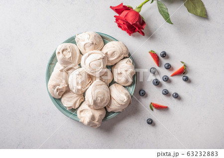 Homemade popular dessert meringue on a plate on white background. Nearby are strawberry and Homemade popular dessert meringue on a plate on white background. Nearby are strawberry and 63232883