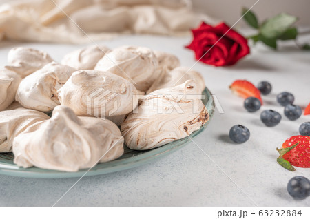 Homemade dessert meringue on a plate on white background. Napkin, strawberry and blueberry berries 63232884