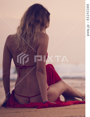 Girl sitting on the beach on a cloudy day with her Girl sitting on the beach on a cloudy day with her 63243389