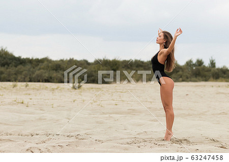 Sensual slim female in black swimsuit on beach 63247458