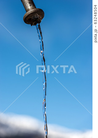Fresh water flowing from a faucet on a clear blue sky 63248504