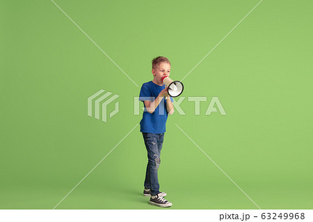 Happy boy playing and having fun on green studio background, emotions 63249968
