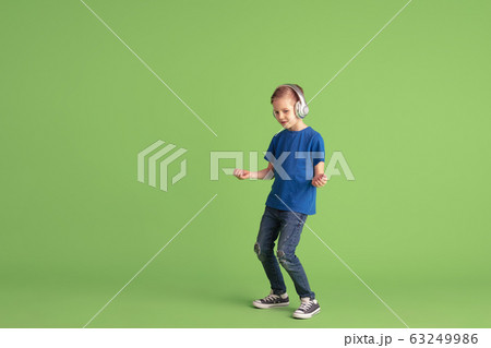 Happy boy playing and having fun on green studio background, emotions 63249986