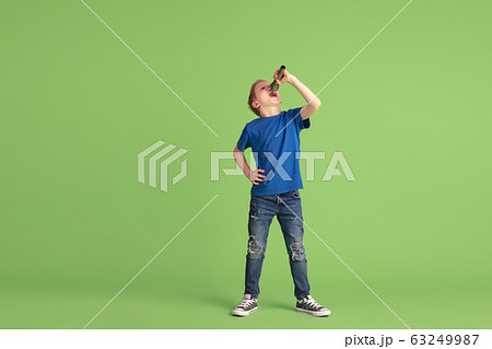 Happy boy playing and having fun on green studio background, emotions 63249987