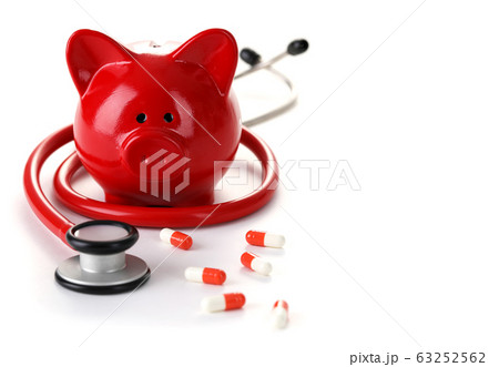 Around piggy bank are stethoscope and capsules 63252562
