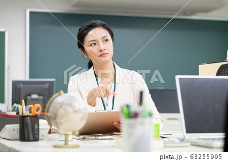 職員室で考え込むミドルエイジの女性教師 63255995