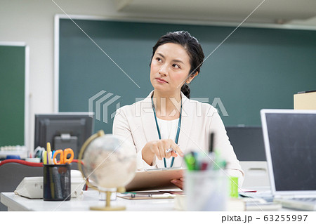 職員室で考え込むミドルエイジの女性教師 63255997