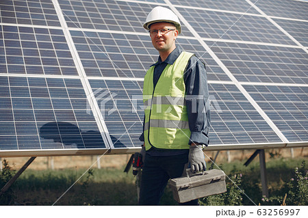 Man in a white helmet near a solar panel 63256997
