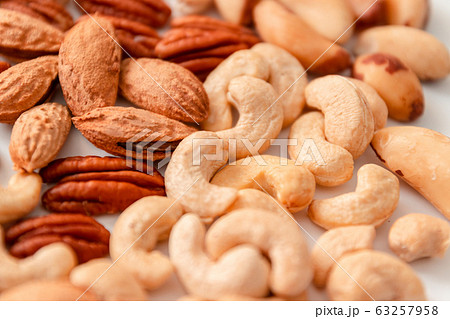 Assorted brown nuts on a gray background. Macadamia, cashews, minced almonds, pecans, wholesome food Assorted brown nuts on a gray background. Macadamia, cashews, minced almonds, pecans, wholesome food 63257958