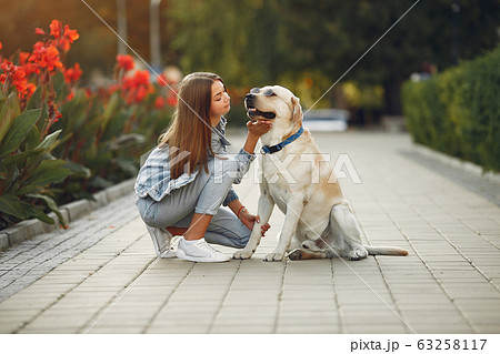 Girl walking in a spring sity with cute dog Girl walking in a spring sity with cute dog 63258117