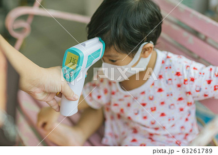 Mother takes temperature for baby boy with Infrared Forehead Thermometer at home 63261789