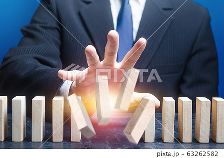 Man destroys order of standing domino row. Spoil plans, ruin business processes. Instability, hit a weak point. Sabotage, ruin a competitor's company. Crime, destabilization of situation, break rules. 63262582