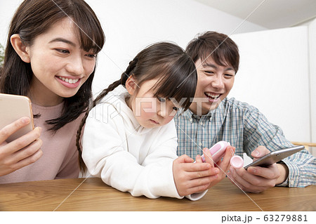 家族イメージ　スマートフォンを持つ両親とキッズケータイを持つ女の子　 63279881