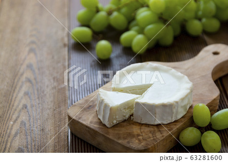 Goat cheeses with grapes, on wooden background isolated. Dark food photo. 63281600