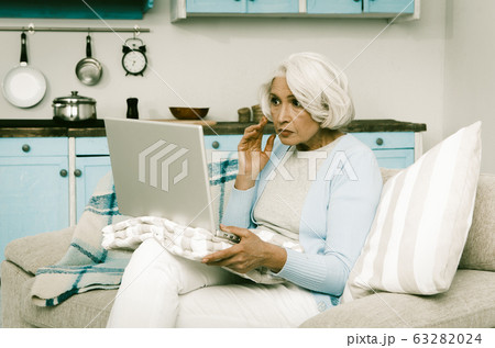 Grandmother Using Laptop Computer At Kitchen Interior Grandmother Using Laptop Computer At Kitchen Interior 63282024