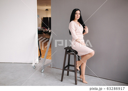 Elegant brunette woman in stylish dress posing in studio on gray background 63286917