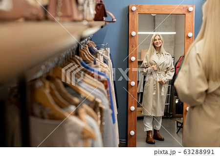 Pretty young stylish female standing in front of mirror in boutique Pretty young stylish female standing in front of mirror in boutique 63288991