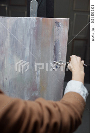 Artist using special tool for painting while applying silver grey paint on paper Artist using special tool for painting while applying silver grey paint on paper 63289131