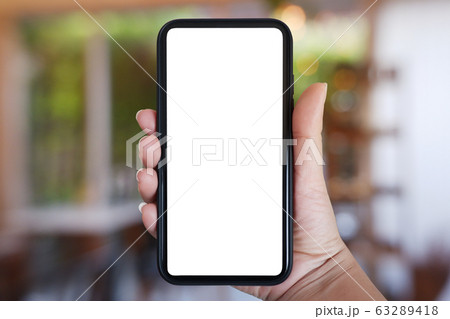 Close-up right hand holding phone vertical, Using smart phone with blurred background of house, cafe interior - copy space Close-up right hand holding phone vertical, Using smart phone with blurred background of house, cafe interior - copy space 63289418