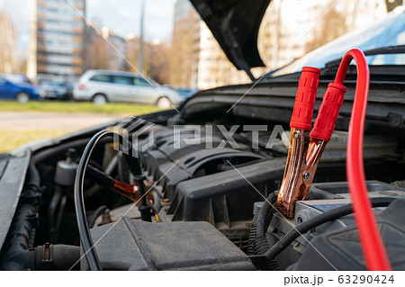 Jump cables on car battery Jump cables on car battery 63290424