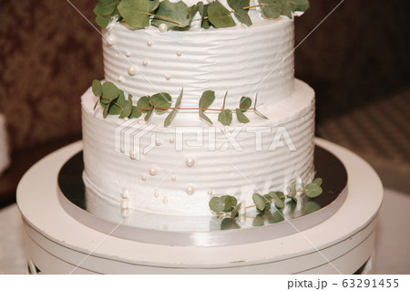 Beautiful white wedding cake with decorated by green leafs 63291455