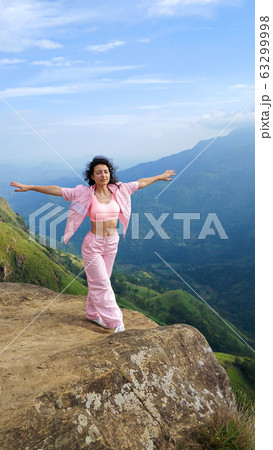 Girl enjoys a mountain view while standing on a Girl enjoys a mountain view while standing on a 63299998