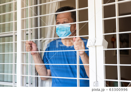 Anxious Chinese man with face mask self isolate at home Anxious Chinese man with face mask self isolate at home 63300996