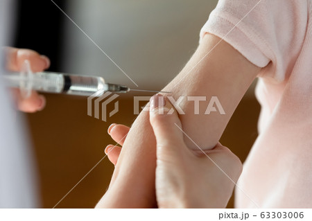 Female doctor making vaccination prick to little patient. Female doctor making vaccination prick to little patient. 63303006