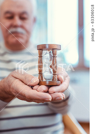 Senior man holding hourglass in retirement home, symbol for limited life 63306018