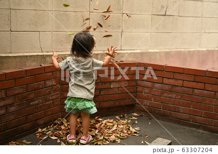 落ち葉で遊ぶ女の子 63307204