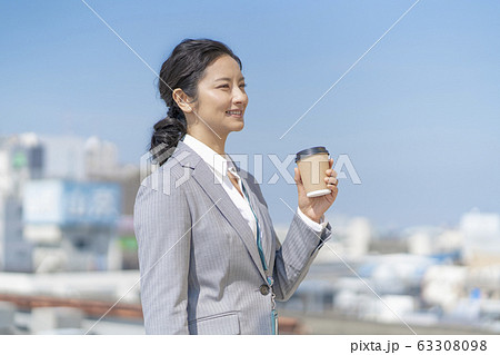 オフィスの屋上で飲み物を飲むながら休憩する女性の写真素材