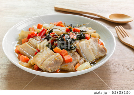 close up of stir fried pork belly with holy basil in a ceramic dish on wooden table. close up of stir fried pork belly with holy basil in a ceramic dish on wooden table. 63308130