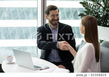 Smiling businesspeople handshake closing deal at briefing Smiling businesspeople handshake closing deal at briefing 63308829
