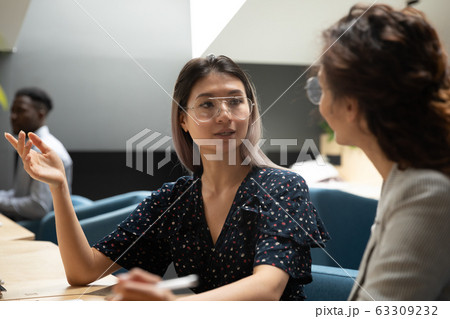Serious Asian businesswoman discussing project with colleague at workplace 63309232
