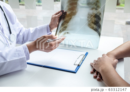 Doctor holding and looking at x-ray film examining 63312147