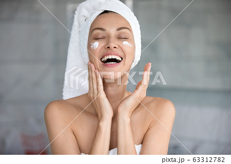 Joyful lady using professional skincare product alone in bathroom. Joyful lady using professional skincare product alone in bathroom. 63312782