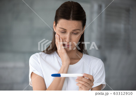 Unhappy frustrated young woman looking at plastic test. 63312910