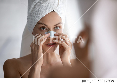 Young beautiful woman applying cleaning strip, removing dark spots. Young beautiful woman applying cleaning strip, removing dark spots. 63312939