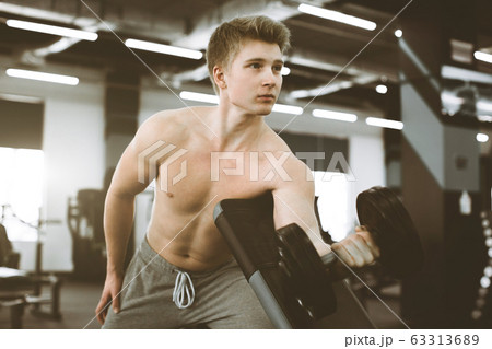 Closeup of a strength fitness man with dumbbell, having workout in the gym. Fit young man with beautiful torso. Beginner Bodybuilder and muscular body concept. 63313689