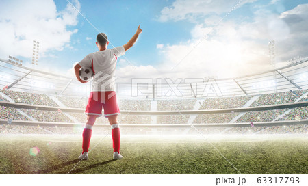 Soccer concept. Soccer player holds a soccer ball on the professional stadium and talking to fans. View from behind. Sport. Sunny 63317793