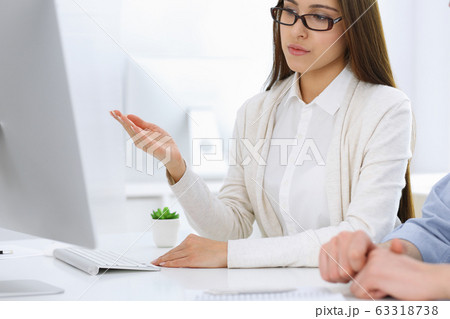 Business woman and man sitting and working with computer in office. Colleagues discussing something at meeting. Corporate teamwork and partnership concepts 63318738