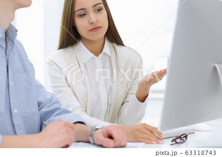 Business woman and man sitting and working with computer in office. Colleagues discussing something at meeting. Corporate teamwork and partnership concepts 63318743