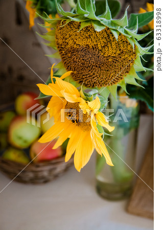 A bouquet with rustic flowers a sunflower stands on a table near a basket with red apples A bouquet with rustic flowers a sunflower stands on a table near a basket with red apples 63318998