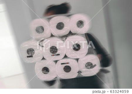 Coronavirus shopping frenzy at store woman carrying many packages of toilet paper in panic buying afraid of shortage in store. Motion blur 63324059