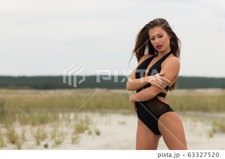 Sensual slim female in black swimsuit on beach 63327520