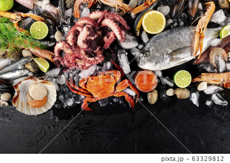Fish and seafood variety, a flat lay top shot. Sea bream. shrimps, crab, sardines, mussels, octopus, scallops and caviar on ice with a place for text Fish and seafood variety, a flat lay top shot. Sea bream. shrimps, crab, sardines, mussels, octopus, scallops and caviar on ice with a place for text 63329812