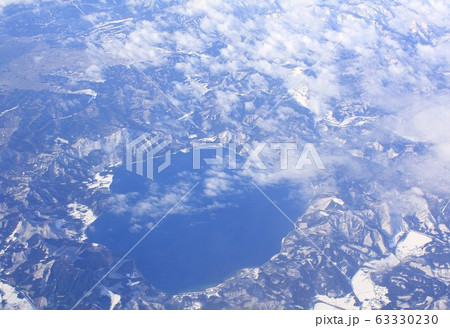 冬の東北地方、秋田県仙北市の山間部に位置する田沢湖を上空の雲間から見る 63330230